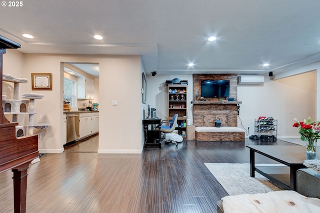 living room featuring hardwood / wood-style flooring, an AC wall unit, and a stone fireplace