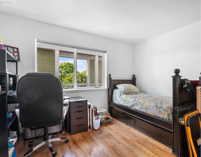 bedroom featuring wood finished floors and a desk