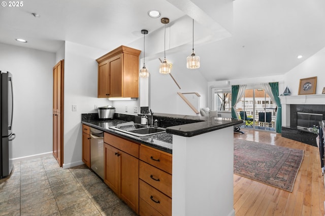 kitchen featuring appliances with stainless steel finishes, a sink, open floor plan, brown cabinets, and recessed lighting