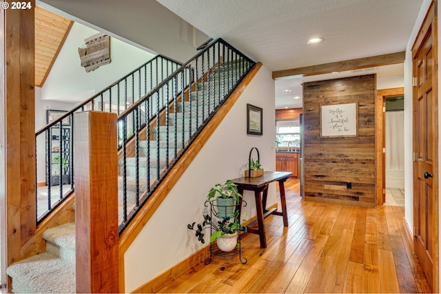 staircase featuring wood walls, hardwood / wood-style floors, and a textured ceiling