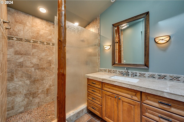 bathroom with vanity, a tile shower, and lofted ceiling