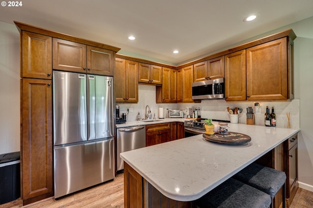 kitchen featuring a breakfast bar, sink, light wood-type flooring, appliances with stainless steel finishes, and kitchen peninsula