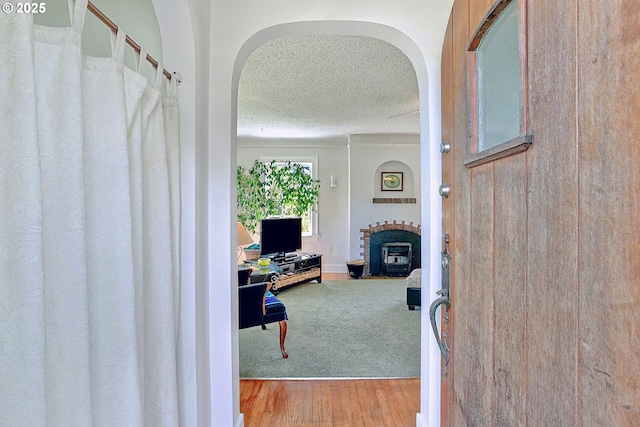 interior space with arched walkways, a textured ceiling, and wood finished floors