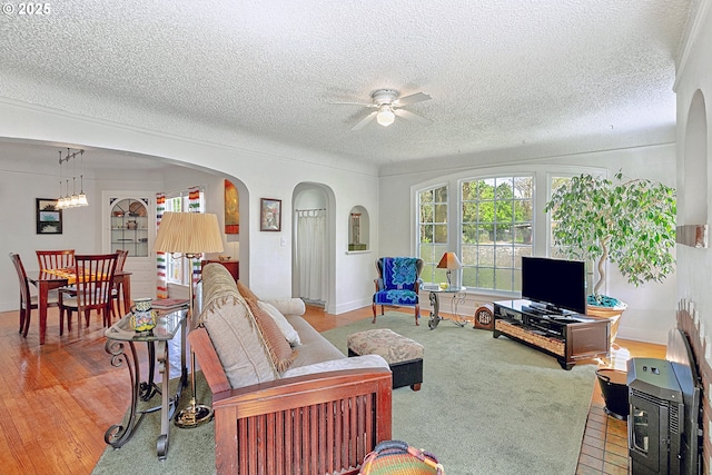 living room with a ceiling fan, a textured ceiling, and arched walkways