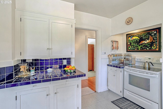 kitchen with decorative backsplash, tile countertops, white electric range, light floors, and white cabinetry