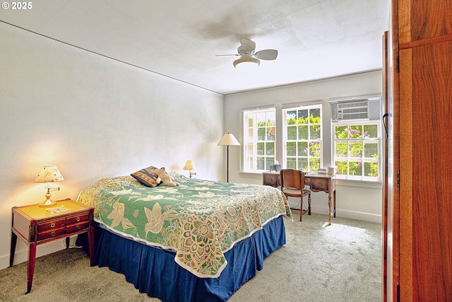 bedroom featuring a ceiling fan, baseboards, carpet, and an AC wall unit