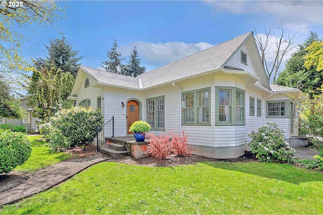 view of front of home with a shingled roof and a front yard