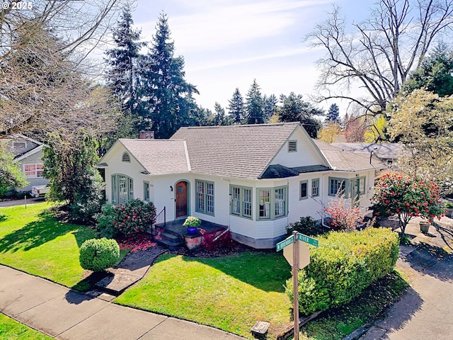 view of front of home featuring a shingled roof and a front yard