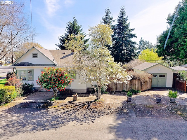 view of front facade with an attached garage, fence, and an outdoor structure