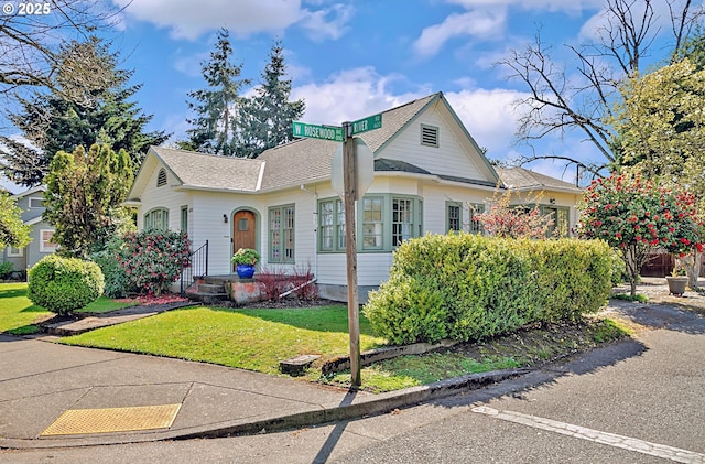 view of front of house with a shingled roof and a front lawn