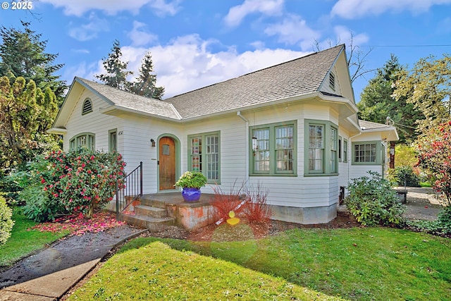 view of front of home featuring a shingled roof and a front yard