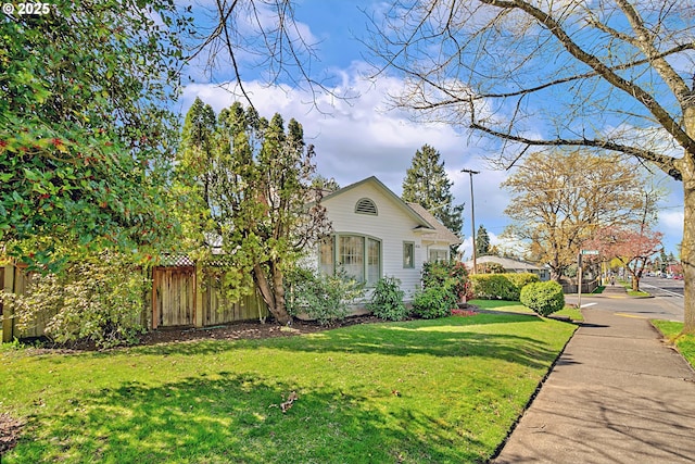 view of home's exterior with fence and a yard