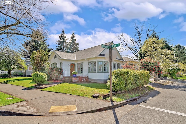 view of front of house featuring a shingled roof and a front lawn