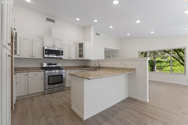 1397 Bonniebrae Dr, Lake Oswego, OR 97034 - kitchen featuring appliances with stainless steel finishes, a peninsula, a sink, light wood-style floors, and light stone counters