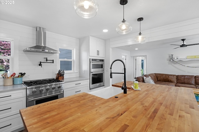 1069 Little Valley Rd, Roseburg, OR 97471 - kitchen featuring stainless steel appliances, wall chimney exhaust hood, butcher block counters, open floor plan, and white cabinetry