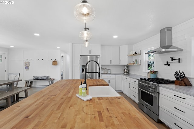 1069 Little Valley Rd, Roseburg, OR 97471 - kitchen featuring appliances with stainless steel finishes, wall chimney range hood, butcher block countertops, pendant lighting, and white cabinetry