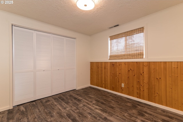 1260 Jackson Ave, Bandon, OR 97411 - unfurnished bedroom with a textured ceiling, dark wood finished floors, ornamental molding, a closet, and wainscoting