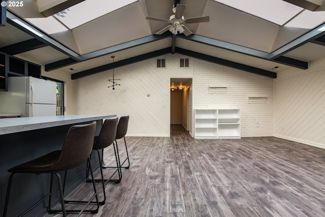 1260 Jackson Ave, Bandon, OR 97411 - kitchen featuring freestanding refrigerator, a ceiling fan, dark wood-style floors, wood walls, and a breakfast bar area