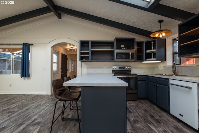1260 Jackson Ave, Bandon, OR 97411 - kitchen featuring stainless steel appliances, open shelves, dark wood finished floors, arched walkways, and a breakfast bar area