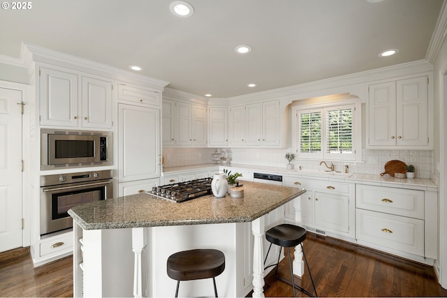 2892 NW Beuhla Vista Ter, Portland, OR 97210 - kitchen featuring appliances with stainless steel finishes, white cabinets, decorative backsplash, a center island, and a breakfast bar area