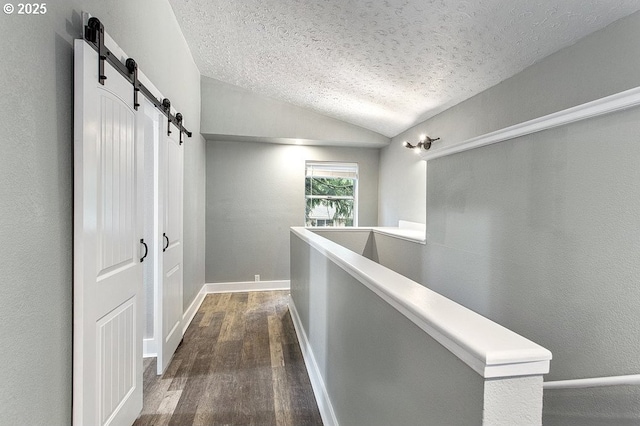 13616 SE Rhine St, Portland, OR 97236 - hallway featuring a textured ceiling, dark wood-style flooring, an upstairs landing, vaulted ceiling, and a barn door