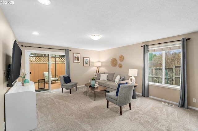 living room featuring baseboards, visible vents, carpet floors, and a textured ceiling