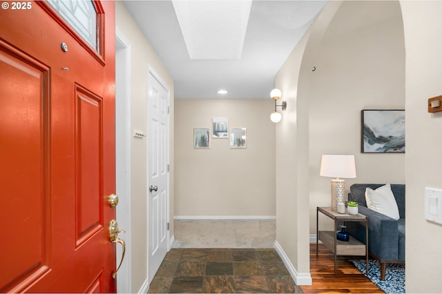 foyer entrance featuring stone finish floor and baseboards