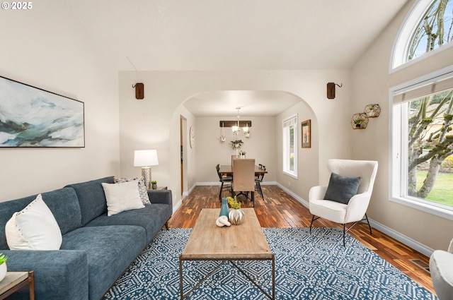 living room with wood finished floors, a healthy amount of sunlight, and arched walkways