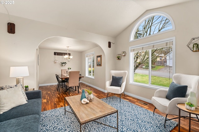 living room with arched walkways, visible vents, wood finished floors, and vaulted ceiling