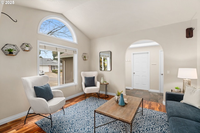 living room featuring baseboards, arched walkways, lofted ceiling, and wood finished floors