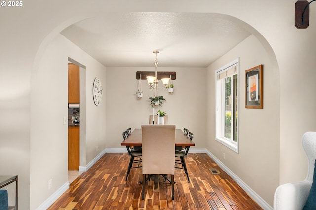 dining space featuring visible vents, baseboards, dark wood-type flooring, and an inviting chandelier