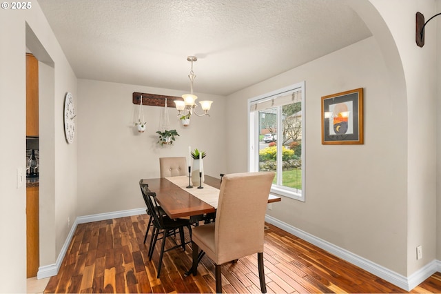 dining room with baseboards, wood-type flooring, and a textured ceiling