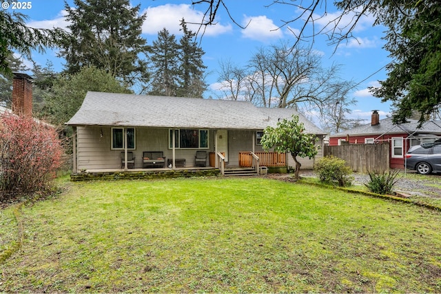 back of property with covered porch, a lawn, and fence