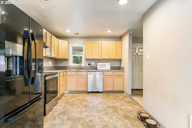 kitchen with light brown cabinets, a sink, recessed lighting, stainless steel appliances, and wall chimney range hood