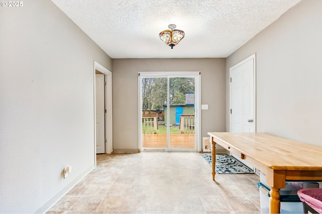 unfurnished dining area featuring baseboards and a textured ceiling