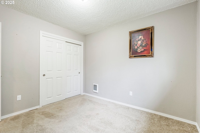 unfurnished bedroom with baseboards, carpet, a closet, and a textured ceiling