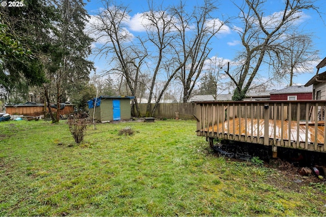 view of yard featuring a storage unit, an outbuilding, a deck, and fence