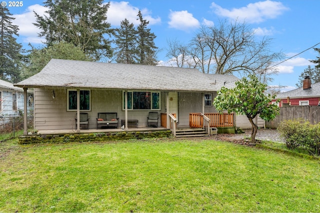 back of property with a lawn and fence