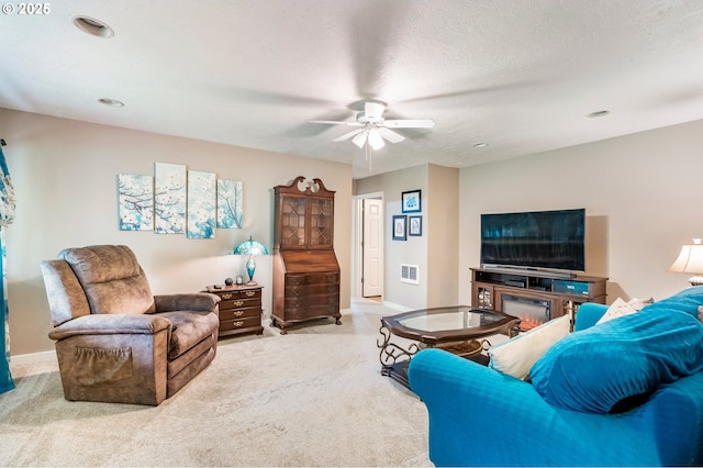 carpeted living room with visible vents, baseboards, a textured ceiling, and ceiling fan