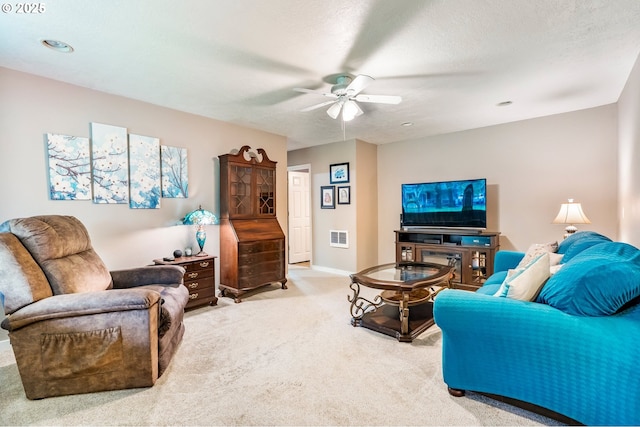 living room featuring visible vents, baseboards, ceiling fan, light carpet, and a textured ceiling