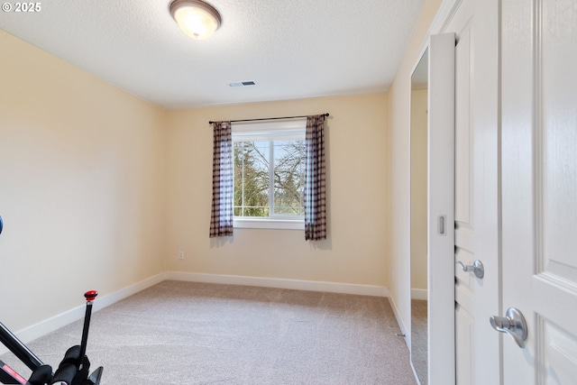 interior space with carpet flooring, visible vents, baseboards, and a textured ceiling