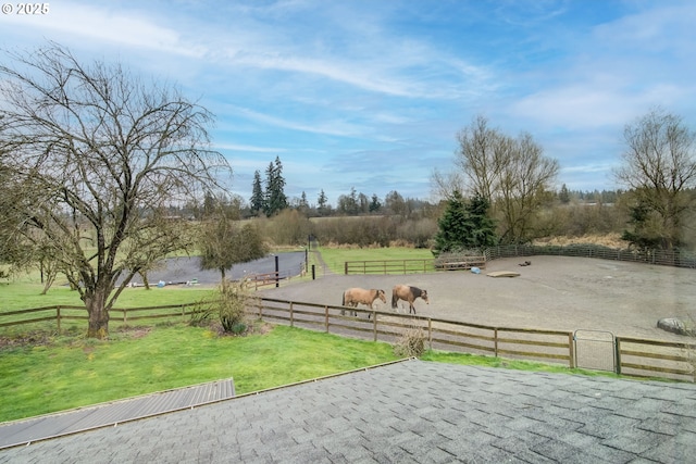 view of property's community featuring an enclosed area, a yard, a rural view, and fence