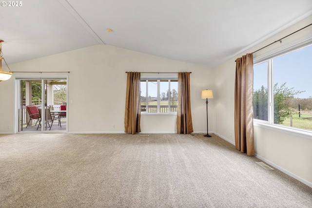 carpeted spare room featuring vaulted ceiling, baseboards, and visible vents