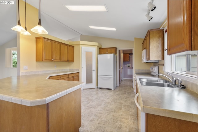 kitchen with lofted ceiling, a peninsula, brown cabinetry, white appliances, and a sink