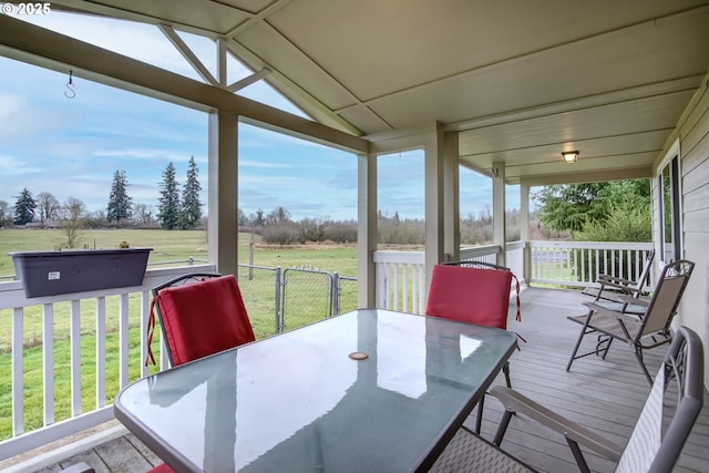 wooden terrace with outdoor dining area and a lawn