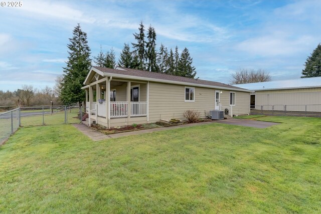 rear view of property with a gate, central AC unit, a yard, and fence