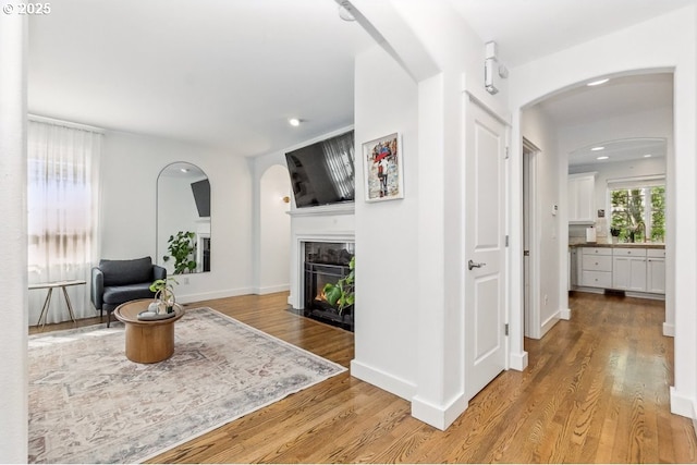 10272 NW Edgewood Dr, Portland, OR 97229 - living room with arched walkways, a fireplace with flush hearth, wood finished floors, recessed lighting, and baseboards