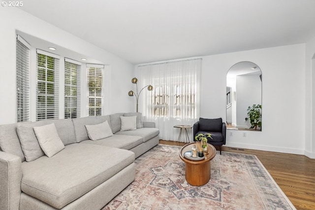 10272 NW Edgewood Dr, Portland, OR 97229 - living room featuring arched walkways, wood finished floors, healthy amount of natural light, and baseboards