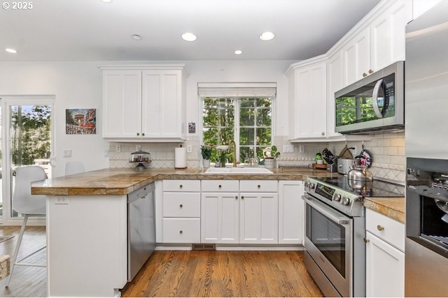10272 NW Edgewood Dr, Portland, OR 97229 - kitchen featuring stainless steel appliances, tile countertops, a peninsula, a sink, and healthy amount of natural light