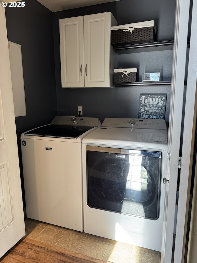 laundry room featuring independent washer and dryer, cabinets, and light tile patterned flooring